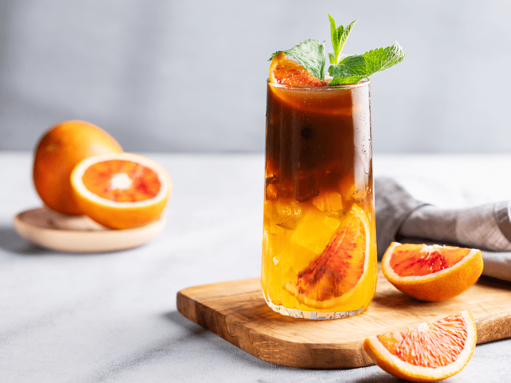 Herbaciany tonic w wysokiej szklance z lodem, pomarańczą i miętą